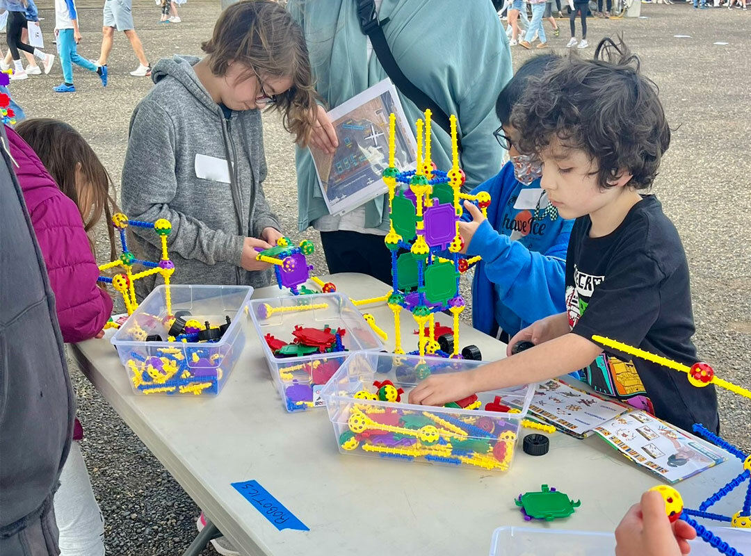 Kids surrounding an activity table doing science projects.