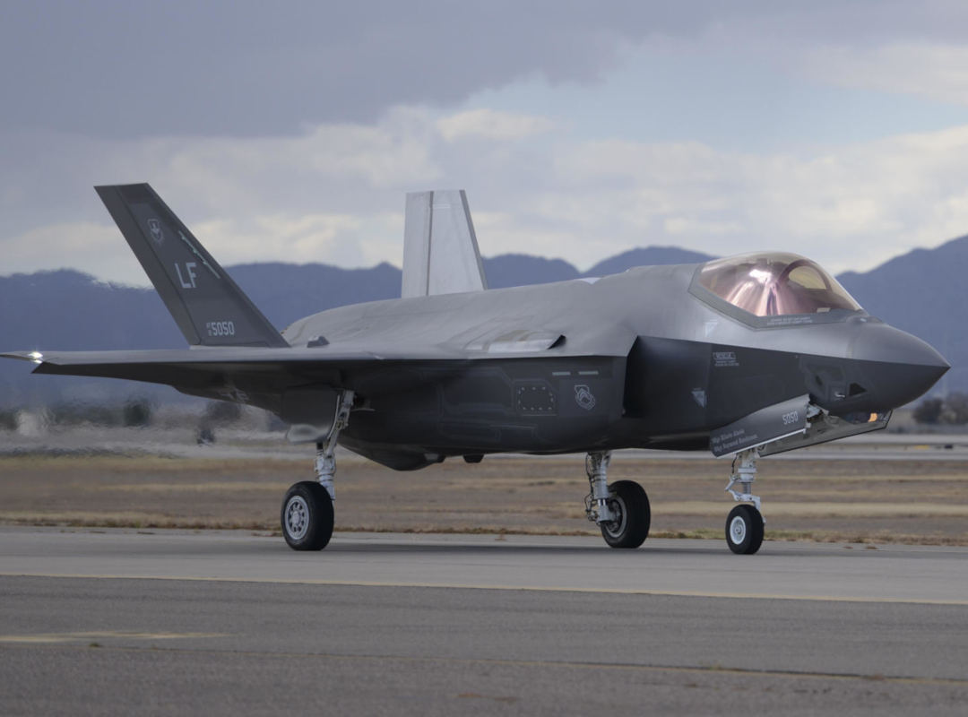 U.S. Air Force F-35 Lightning II stealth fighter taxiing on a runway, shown in profile with landing gear deployed and mountains visible in the background.