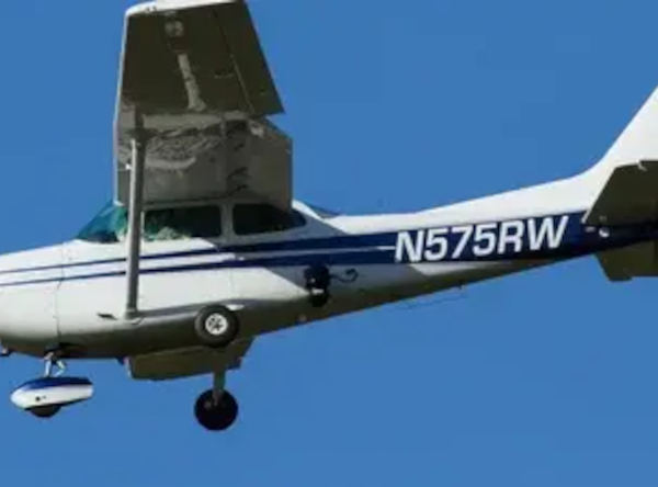 Blue and white Reims/Cessna R-172 N575RW flying against a clear blue sky with fixed landing gear extended.